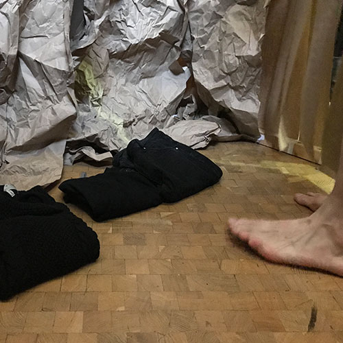 Folded bvlack clothes and two naked feed